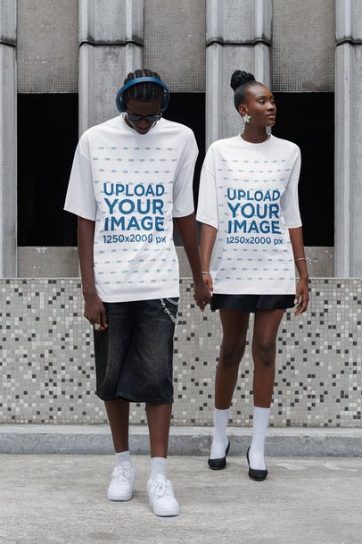 Mockup of a Couple Holding Hands in the Street While Wearing Oversized T-Shirts