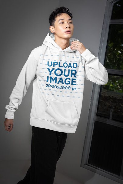 Pullover Hoodie Mockup of a Man Posing Near a Window With a Serious Look m54164