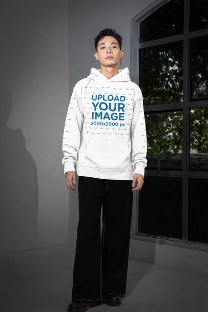 Hoodie Mockup Featuring a Man With Customizable Sleeves Posing Near a Window m54163