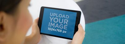 Tablet Mockup of Young Woman Using a Black iPad at Office Lounge