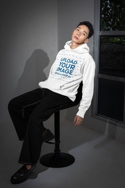 Alternative-Styled Mockup of a Man in a Pullover Hoodie Sitting on a Chair in a Room m54168
