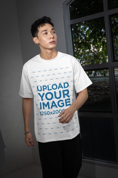Oversized T-Shirt Mockup Featuring a Man Posing With a Serious Look and Standing Near a Window m54148