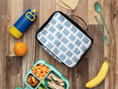 Mockup of a Sublimated Lunch Bag Placed on a Wooden Table and Surrounded by Kids' Snacks  m57818