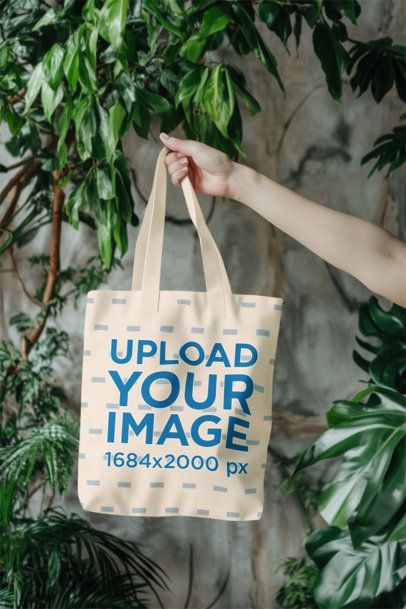 Mockup Featuring an AI-Created Hand Holding a Tote Bag Against a Wall With Plants m55070