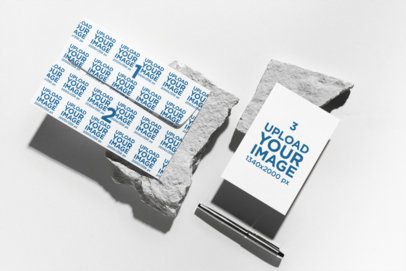 Mockup Featuring an Envelope and a Postcard Placed Over Two Rocks