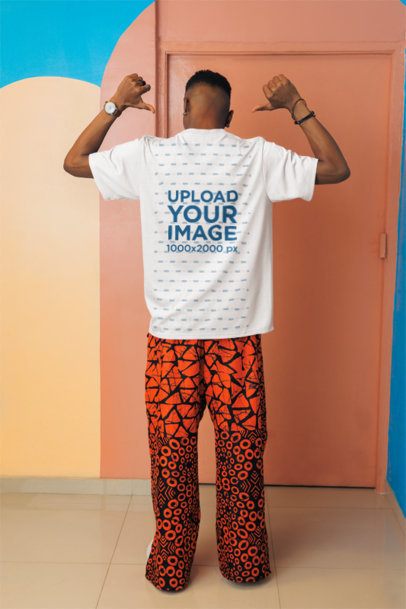 Back-View Mockup of a Man Pointing at His Round-Neck T-Shirt While Standing Against an Artsy Wall