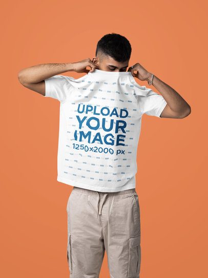 Mockup of a Man Taking Off His Oversized T-Shirt in a Studio Setting m57443
