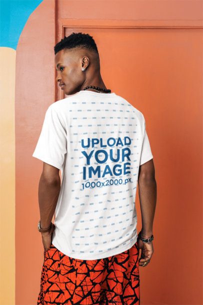 Back-View T-Shirt Mockup of a Man Posing Against an Artsy Colorful Wall