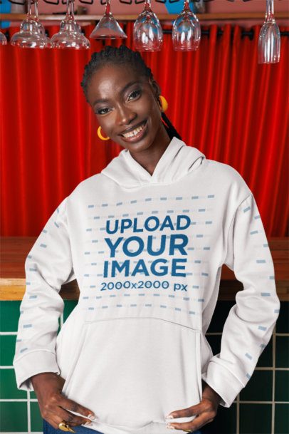 Pullover Hoodie Mockup of a Smiling Woman Posing Against a Bar