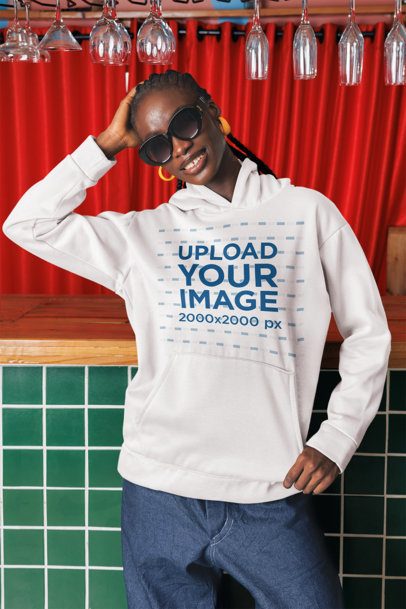 Pullover Hoodie Mockup Featuring a Smiling Woman With Sunglasses Posing in a Bar