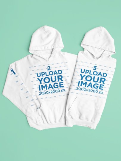 Mockup of Two Gildan Pullover Hoodies Lying on a Colorful Backdrop m52197