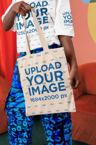 Oversized T-Shirt Mockup of a Cropped-Face Woman Carrying a Tote Bag in a Living Room