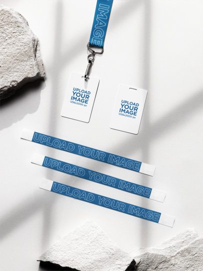 Wristband Mockup Featuring Two Badge Holders and a Lanyard Lying on a Surface With a Rock m58150