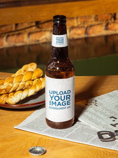 Ambar Beer Bottle Mockup Featuring a Bar Table With a Newspaper and Some Snacks m58060