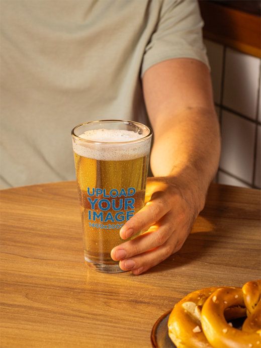 Mockup of a Man's Hand Holding a Shaker Pint Glass Filled With Beer
