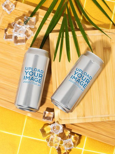 Mockup of Two 16 Oz Cans Lying on a Wooden Surface and a Tropical-Inspired Setting