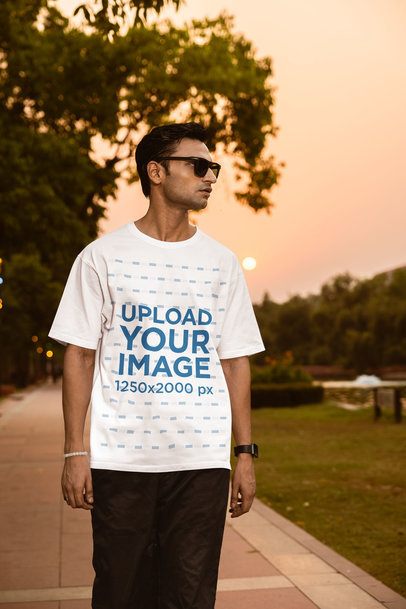 Oversized T-Shirt Mockup of a Man Walking in the Street With a Nice Sunset View