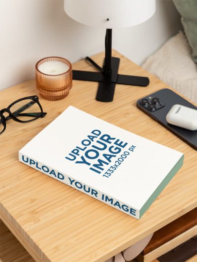 Mockup Featuring a Paperback Book Placed on a Wooden Nightstand