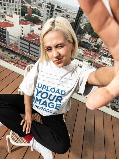 Oversized T-Shirt Mockup Featuring a Woman Posing on a Roof While Winking m57624