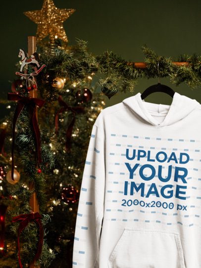 Mockup of a Comfort Colors 1567 Garment-Dyed Hoodie on a Hanger Next to a Christmas Tree m59337