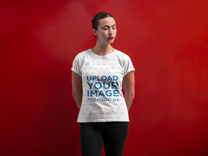 Mockup of a Woman Wearing a T-Shirt Against a Red Wall