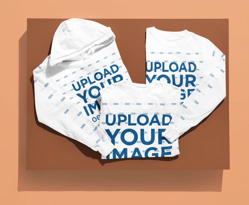 Apparel Bundle Mockup featuring a Folded Hoodie, T-Shirt, and Long Sleeve Shirt on a Two-Tone Flat Lay Surface