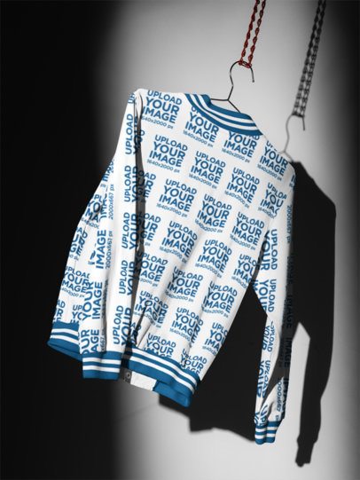 Varsity Jacket Mockup featuring a Back View Hanging on a Wire Hanger in a Dramatic Studio Setting m59792