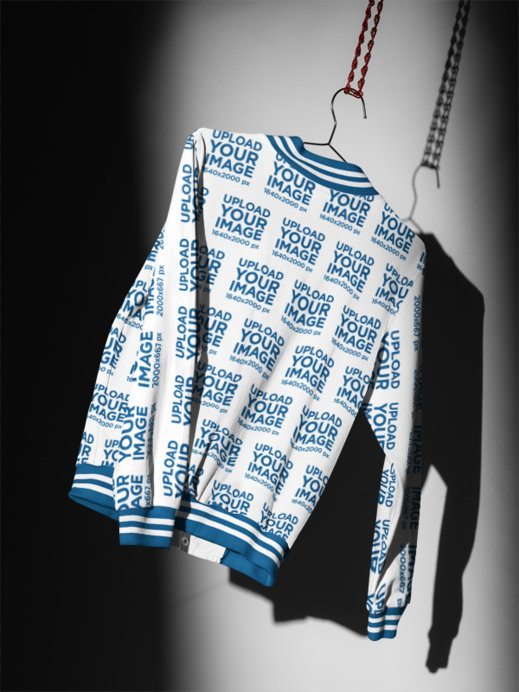 Varsity Jacket Mockup featuring a Back View Hanging on a Wire Hanger in a Dramatic Studio Setting