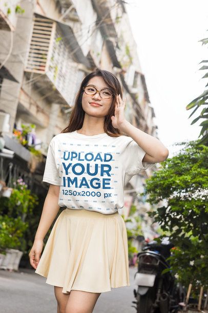 Short Sleeve T-Shirt Mockup with a Cheerful Woman in a K-Drama Inspired Pleated Skirt Standing on an Outdoor Alley m55322