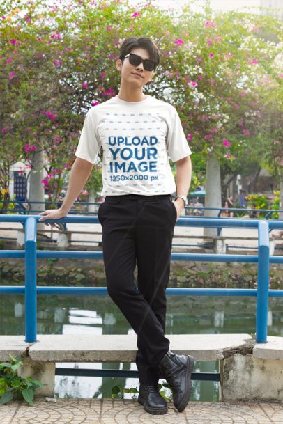 T-Shirt Mockup featuring a Cool Young Man in Sunglasses Leaning on a Blue Railing with a K-Drama Vibe Outdoors m55307