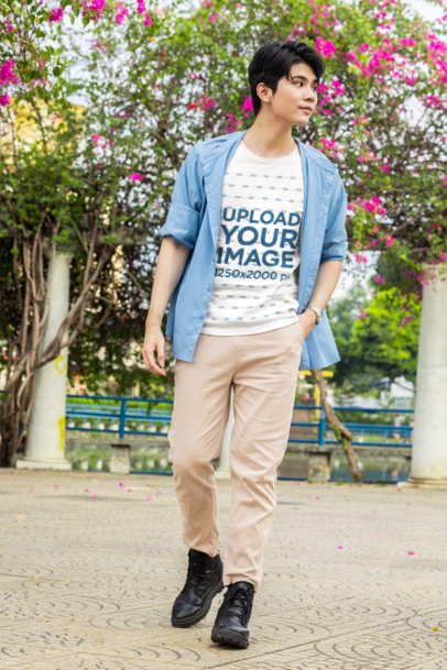 T-Shirt Mockup featuring a young man with a K-drama style walking in an outdoor park m55316