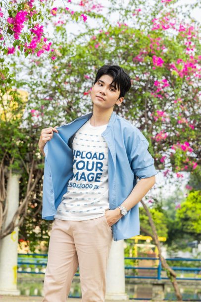 T-Shirt Mockup featuring a young man with a K-drama look adjusting his shirt in a park m55315