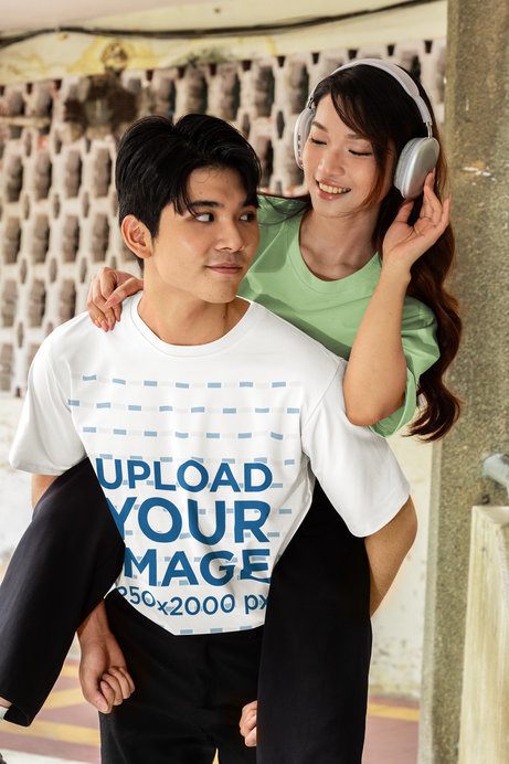Oversized T-Shirt Mockup featuring a Young Man Carrying a Smiling Woman in a Romantic K Drama Inspired Moment Outdoors
