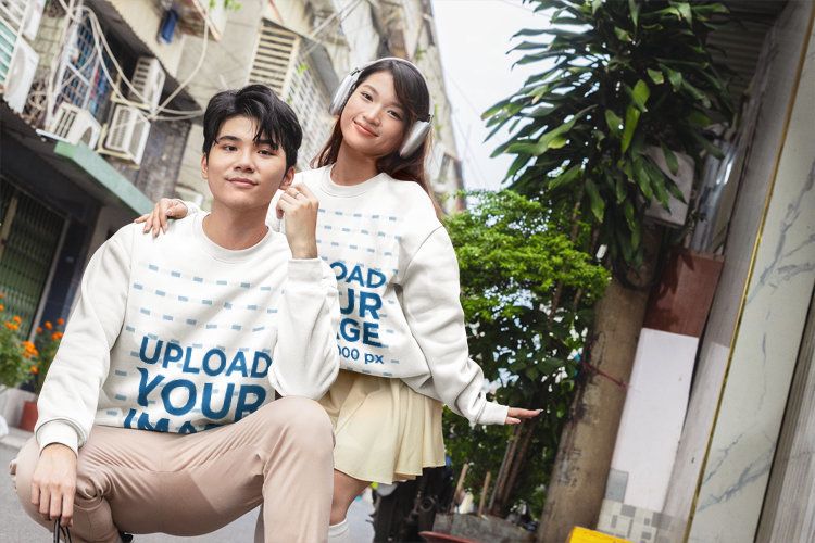 Matching Sweatshirt Mockup Featuring a Smiling K-Drama Couple Posing Together on an Urban Street