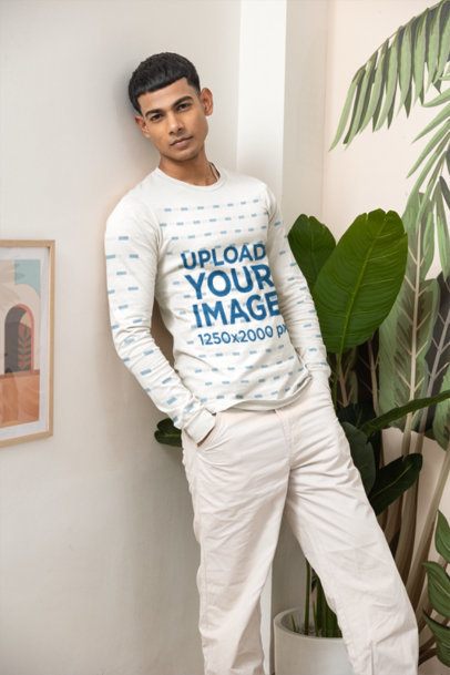 Long Sleeve T-Shirt Mockup Featuring a Young Man Leaning Against a Wall Indoors Next to Tropical Decor m55396