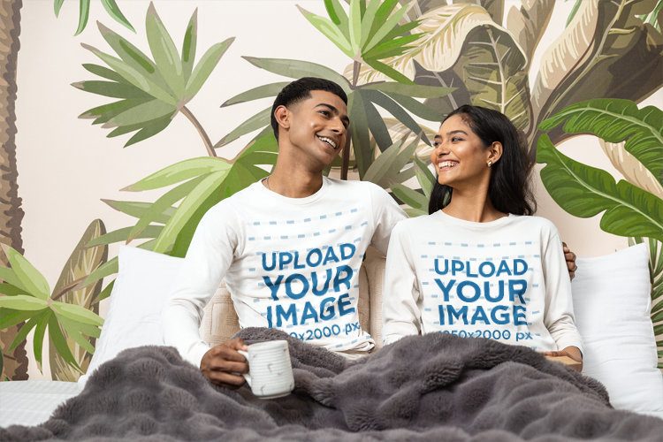 Long Sleeve T-Shirt Mockup of a Happy Couple Relaxing under a Blanket in a Cozy Bedroom