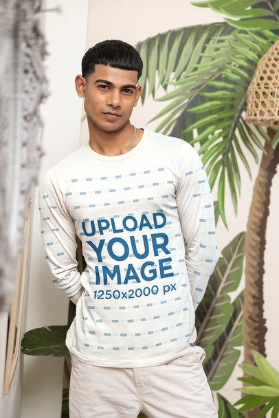 Long Sleeve Shirt Mockup Featuring a Young Man Posing with Hands Behind His Back in a Room with Tropical Wallpaper m55397