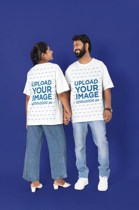 T-Shirt Mockup featuring a Couple Holding Hands and Smiling at Each Other in a Studio