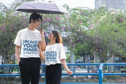 K-Drama Inspired T-Shirt Mockup Featuring a Young Couple Holding an Umbrella in the Rain