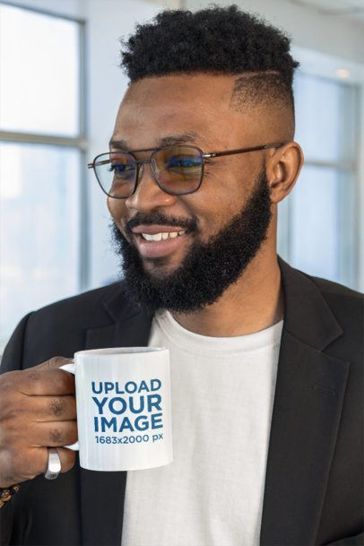 Coffee Mug Mockup Featuring a Smiling Bearded Man With Glasses Holding a Drink in a Bright Modern Office