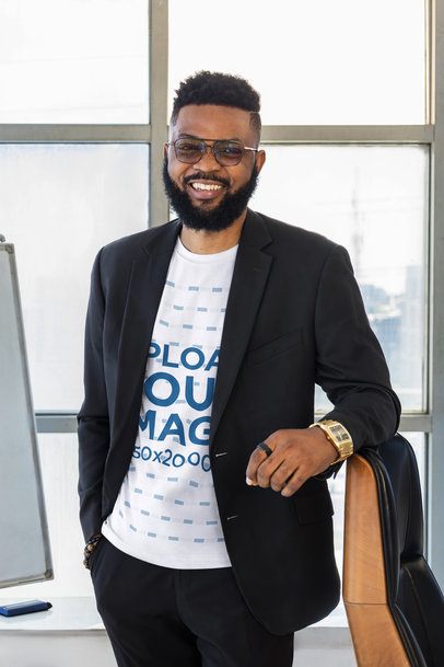 T-Shirt Mockup Featuring a Smiling Black Man Leaning on an Office Chair Near a Window