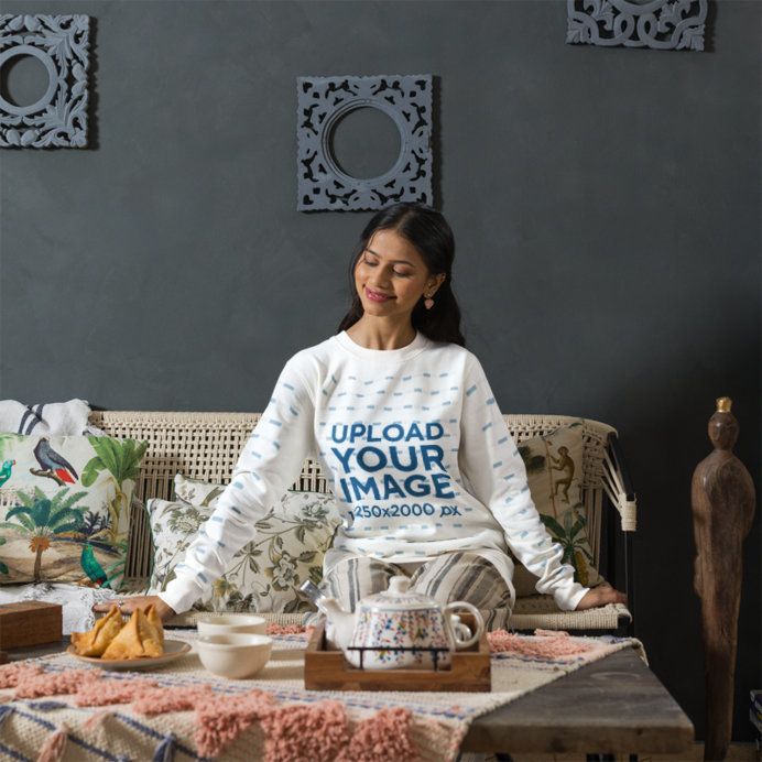 Sweatshirt Mockup Featuring a Smiling Woman Sitting on a Woven Sofa in a Cozy Living Room