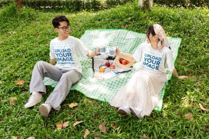 T-Shirt and Mug Mockup Featuring a Smiling Couple Toasting on a Picnic Blanket in a Park