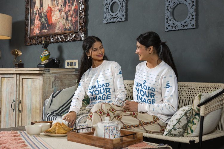 Crewneck Sweater Mockup of Two Young Women Looking at Each Other Sitting Indoors With Tea