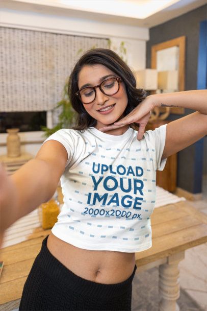 Short Sleeve Crop Top Mockup With a Young Woman Taking a Selfie in a Cozy Dining Room