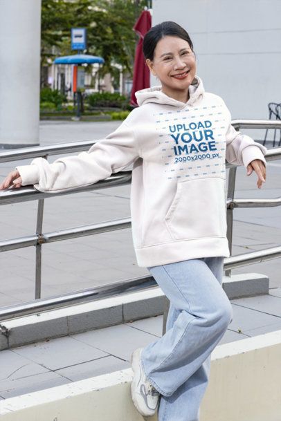 Hoodie Mockup Featuring a Smiling Mature Woman Leaning on a Metal Railing in an Urban Plaza m55961