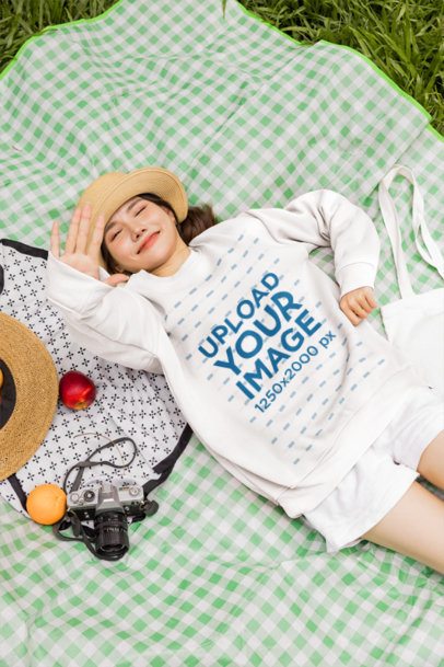 Pullover Mockup With a Young Woman Relaxing on a Picnic Blanket in the Grass