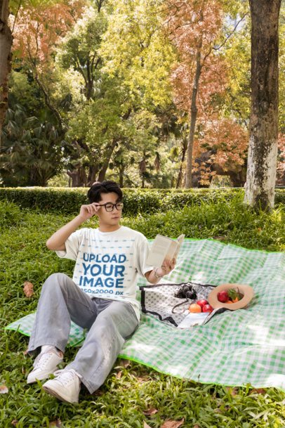 T-Shirt Mockup Featuring a Young Man Reading a Book on a Picnic Blanket in a Park m57794