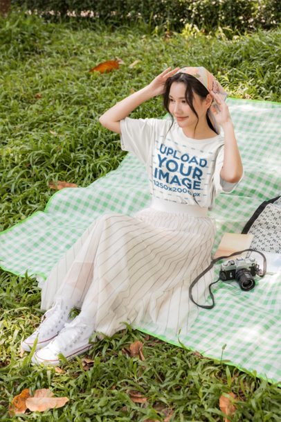 White Tee Mockup of a Smiling Woman Sitting on a Checkered Mat in the Grass m57797