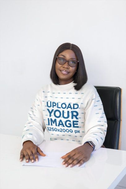 Sweatshirt Mockup Featuring a Smiling Woman Wearing Glasses Sitting at a White Corporate Desk